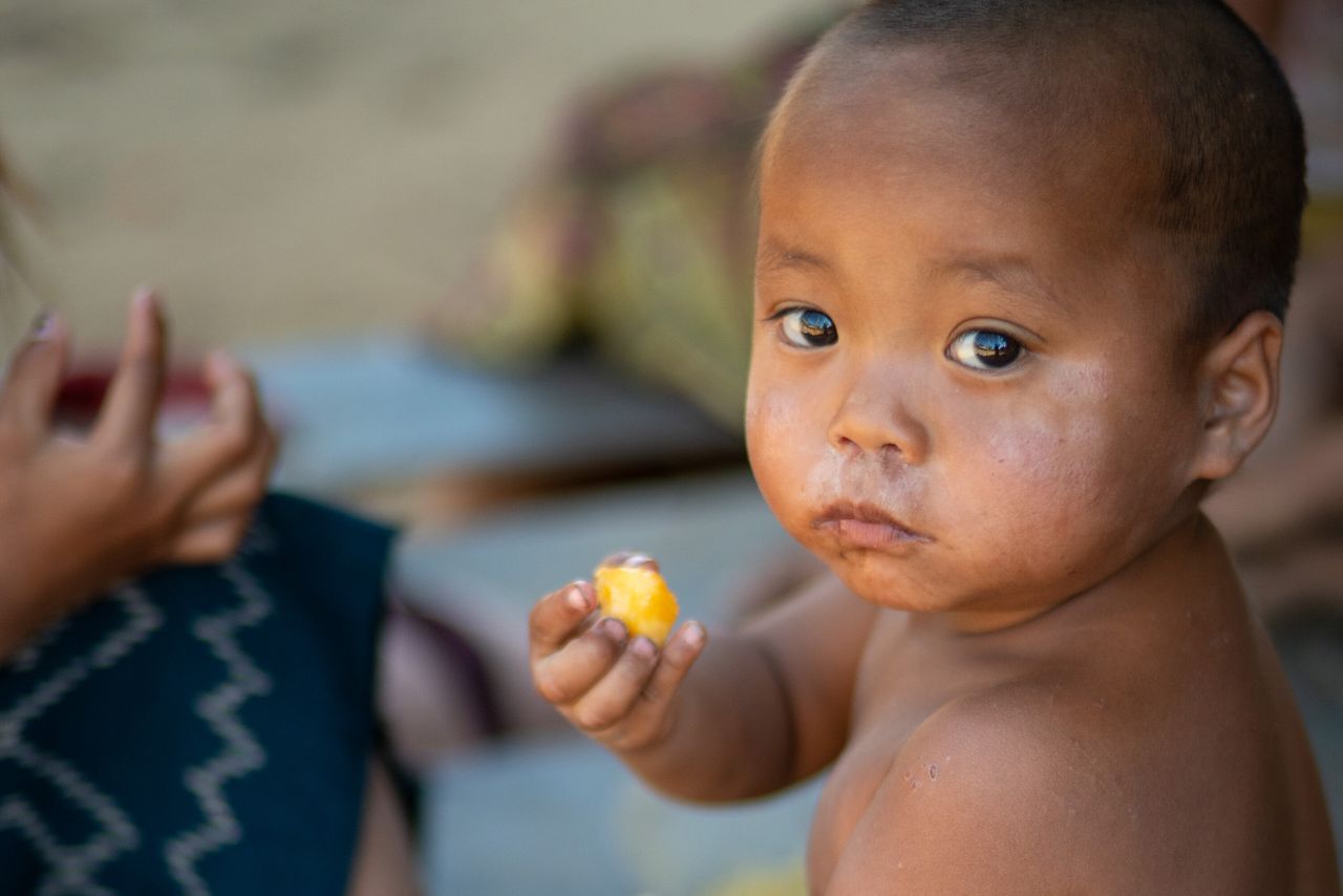 services-03 A child enjoying a piece of fruit, showcasing rural life in Laos.
